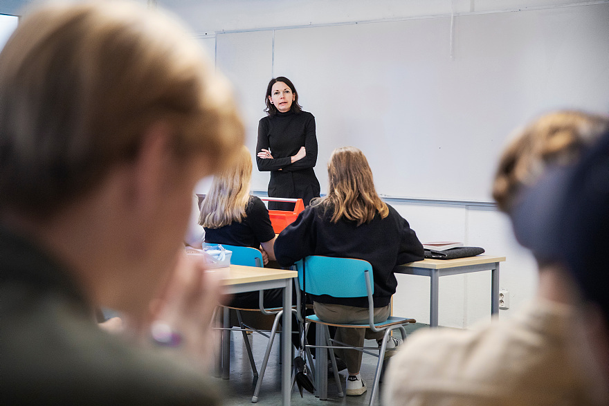 En lärare står framför elever i ett klassrum.